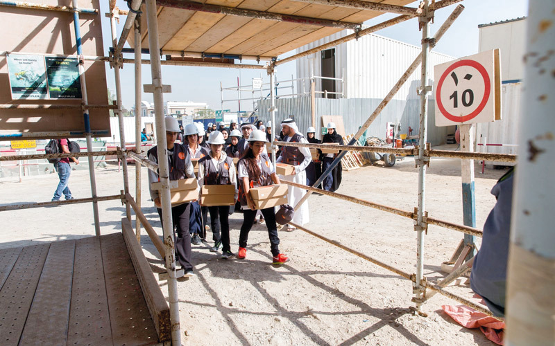 شما بنت محمد وطلاب مدارس في دبي يوزعون الطعام على العمال