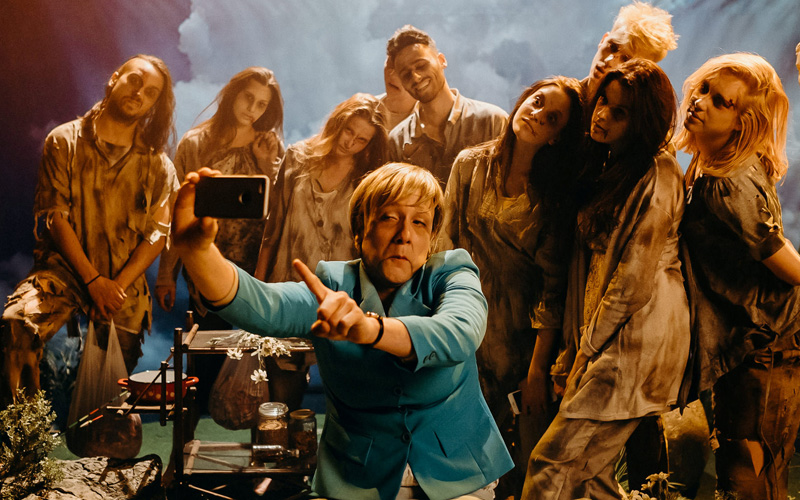 الفنان يصور ميركل وخلفها مجموعة من اللاجئين.