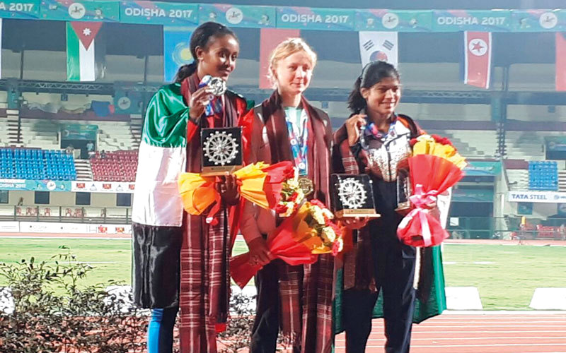 علياء (يسار) تتوشح العَلم الإماراتي على منصة التتويج. من المصدر