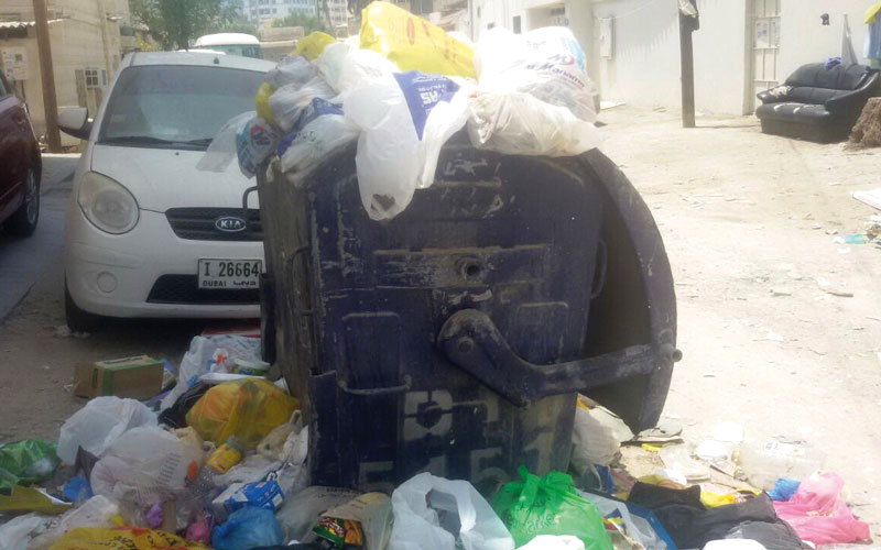 حاويات قمامة تفيض بأكياس النفايات في منطقة البستان. الإمارات اليوم