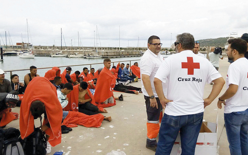 رجال «الصليب الأحمر الإسباني» يتابعون أحوال مجموعة من المهاجرين بعد أن تم انتشالهم من أعماق البحر. إي.بي.إيه