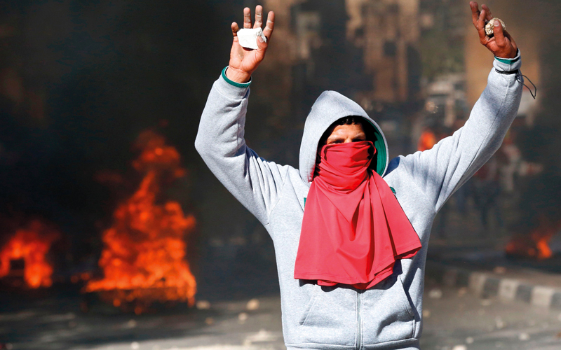 فلسطيني يرفع حجراً في وجه الاحتلال خلال تظاهرات الخليل. أ.ف.ب