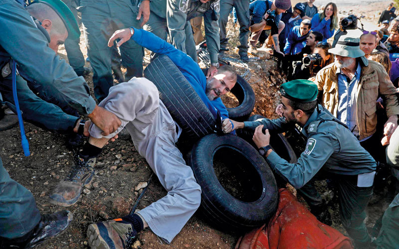 الجيش الإسرائيلي يحاول ظاهرياً إجلاء مستوطنين بالقوة من أراضي الفلسطينيين التي استولوا عليها.  أ.ف.ب