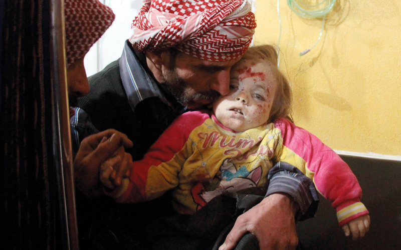 رجل يحمل جثة طفلته التي قُتلت في غارات للنظام على مدينة دوما. أ.ف.ب