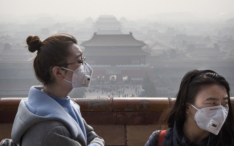 سيدتان تغطيان وجهيهما بقناعين اتقاءً لآثار التلوث المستمرة في بكين.  غيتي