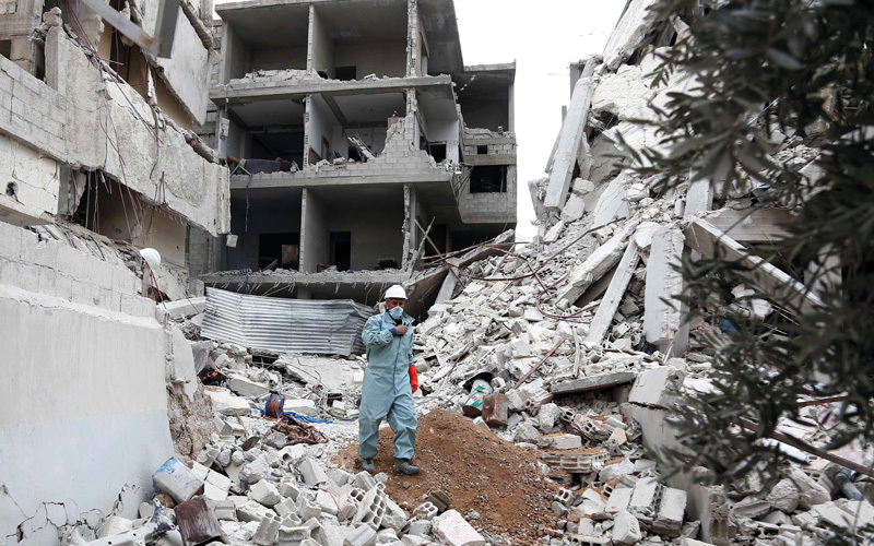 أحد المتطوعين من رجال الدفاع المدني يمشي وسط الركام  في بلدة حزا بالغوطة الشرقية. أ.ف.ب