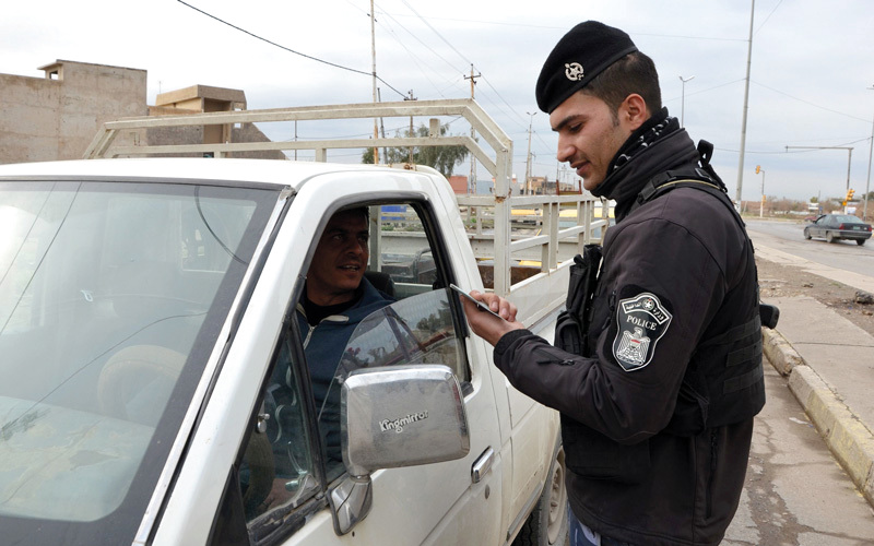 شرطي عراقي يتحقق من هوية سائق في نقطة تفتيش بالموصل. أ.ف.ب