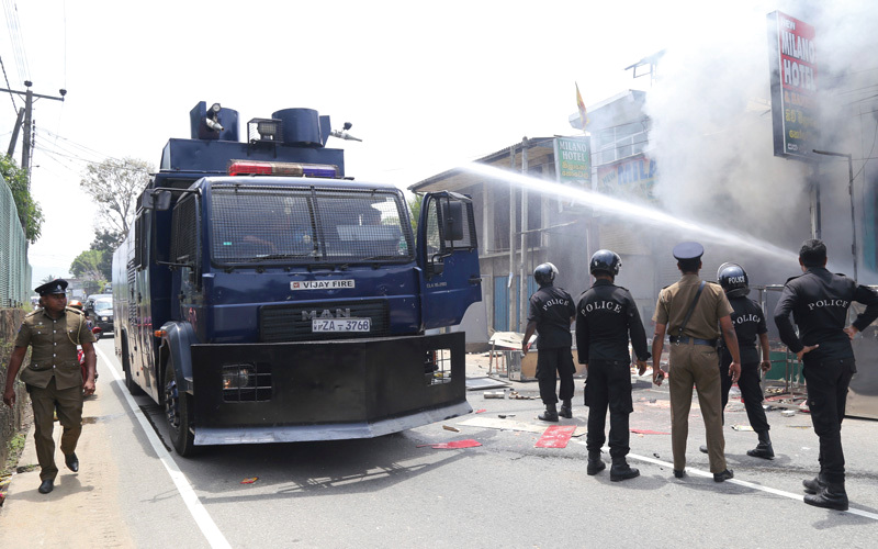ضباط من الشرطة السريلانكية يحاولون إطفاء حريق بمحال  في أمباتينا وسط البلاد. أ.ب