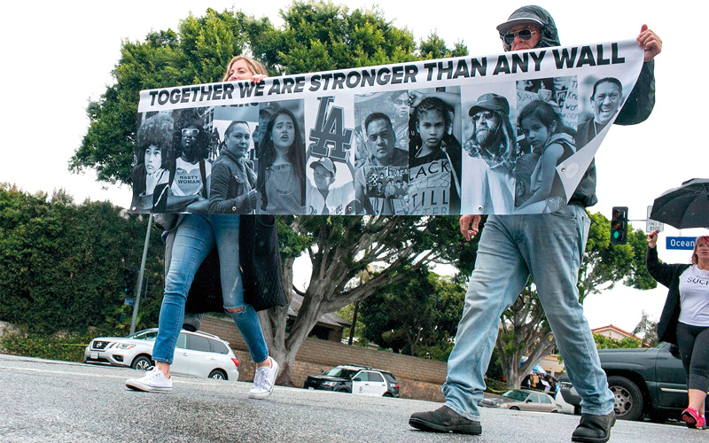 محتجون ضد الرئيس ترامب يحملون لافتة كتب عليها «معاً نحن أقوى من أي جدار». أ.ف.ب