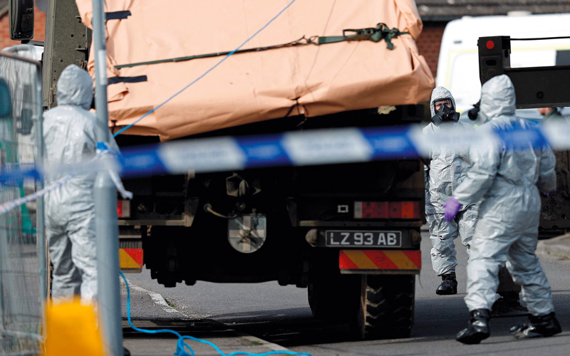 خبراء عسكريون بريطانيون يرتدون أزياء واقية يحاولون التحفظ على مركبة ذات صلة بهجوم غاز الأعصاب في سالسبوري.  أ.ف.ب
