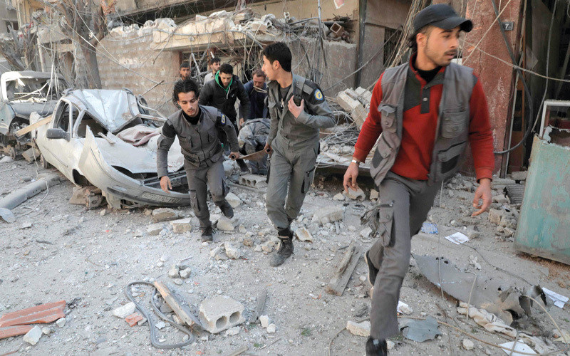 مسعفون يبحثون عن ضحايا تحت الأنقاض بعد القصف على الغوطة الشرقية.  أ.ف.ب