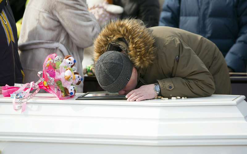 رجل يقبّل صورة ضحية أثناء تشييع جنازته في مقبرة كيميروفو.  رويترز