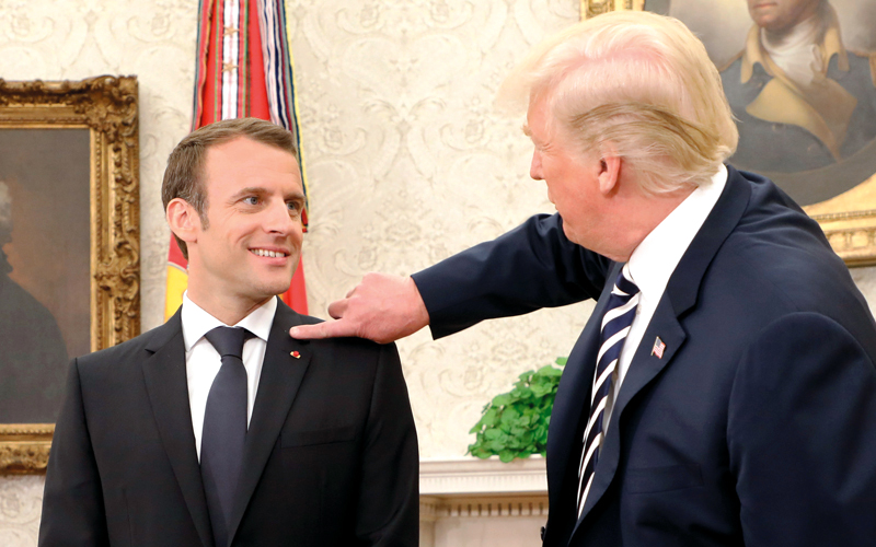 ترامب يزيح قشرة رأس ماكرون من على ثيابه. أ.ف.ب