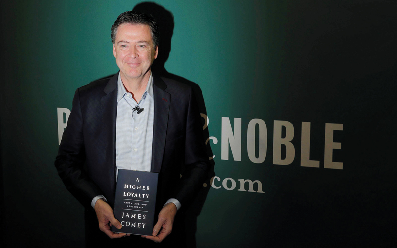 كومي ممسكاً بكتابه الذي قد يهز عرش ترامب. رويترز