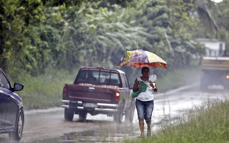 امرأة تمشي على جانب أحد الطرق خلال هطول الأمطار الغزيرة في هافانا. إي.بي.إيه