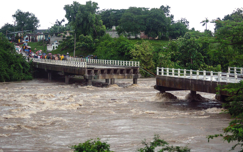 سكان بلدة زازا ديل ميديو ينظرون إلى جسر منهار بسبب الأمطار الغزيرة. أ.ف.ب