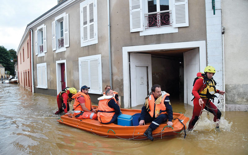 رجال إطفاء فرنسيون يرتدون ملابس الغوص.. ينقلون الناس  في قارب صغير على طول الشارع الرئيس المغمور بالفيضانات في مدينة سوليني سو بالون. أ.ف.ب