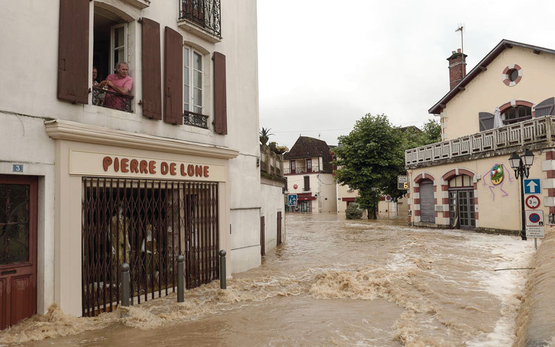 رجل ينظر من النافذة لمشاهدة مياه الفيضانات التي تجتاح الشوارع بعد هطول الأمطار الغزيرة في ساليس دي بيرن جنوب غرب فرنسا. أ.ف.ب