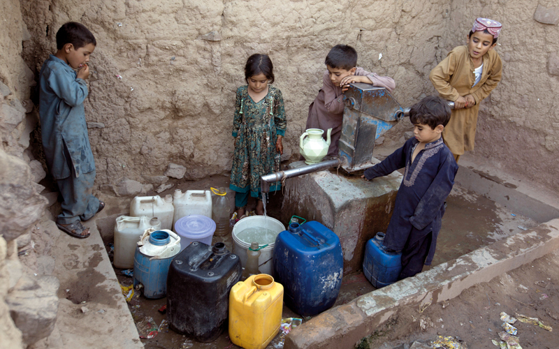 مجموعة من أطفال اللاجئين الأفغان هربوا من الحرب والمجاعة يتجمعون  أمام صنبور مشترك لتعبئة المياه. أ.ب
