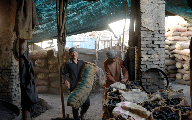 مجموعة من العمال المهاجرين الأفغان يعملون في استخراج الفحم بسوق في مزار الشريف.  أ.ف.ب