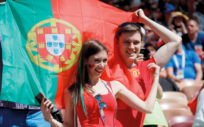 مشجعان برتغاليان يتوشّحان بعلم بلدهما، قبل انطلاق مباراة البرتغال والمغرب أمس. رويترز