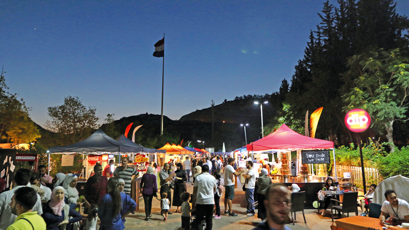 سوريون يتوافدون على «شارع الطعام» الذي افتتح أخيراً في حديقة تشرين بالعاصمة دمشق.  إي.بي.إيه