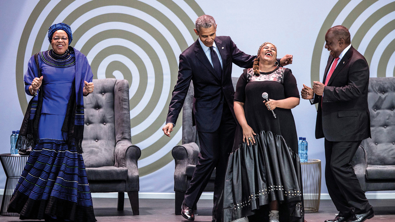 أوباما وأرملة مانديلا غراسا ميشيل «إلى اليسار» ورئيس جنوب إفريقيا رامافوسا يغنون ويرقصون أثناء الاحتفال بذكرى ميلاد الزعيم نيلسون مانديلا.  أ.ف.ب