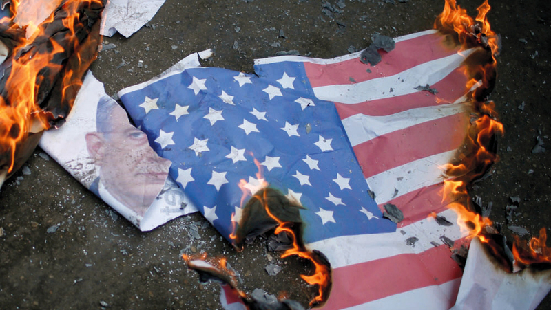 متظاهرون يحرقون العلم الأميركي وصورة لنتنياهو أثناء تظاهرة في غزة. أرشيفية