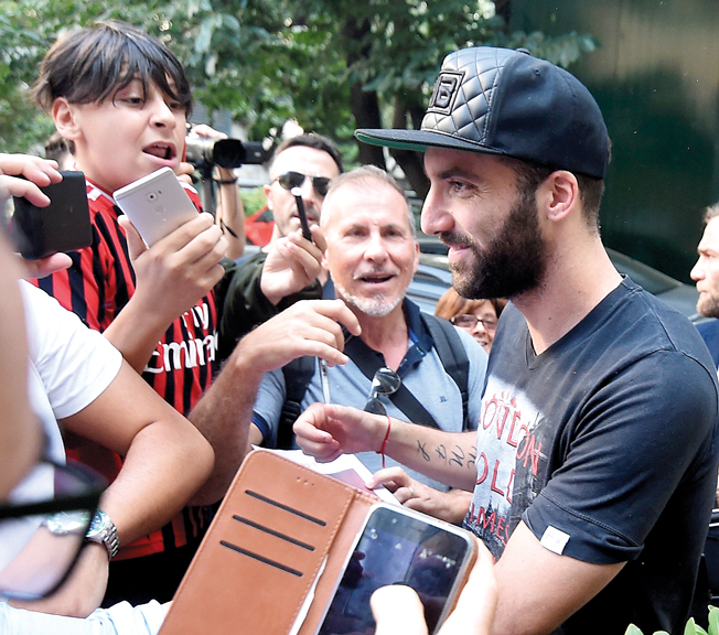 هيغواين خلال وصوله إلى ميلان محاطاً بمشجعي أنصار «الروسينيري». رويترز