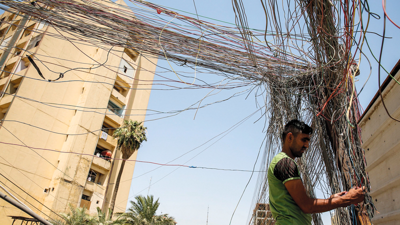 فني يفحص اسلاك الكهرباء المتهالكة في بغداد. ا.ف.ب