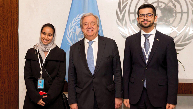 الأمين العام للأمم المتحدة أنطونيو غوتيريس متوسطاً ممثلَين من برنامج الإمارات للمندوبين الشباب. من المصدر