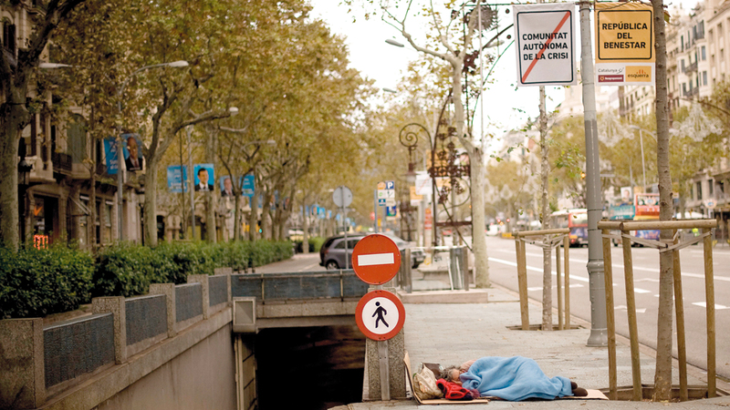 مشرد ينام على رصيف أثناء الانتخابات العامة الإسبانية في برشلونة شتاء 2011. غيتي