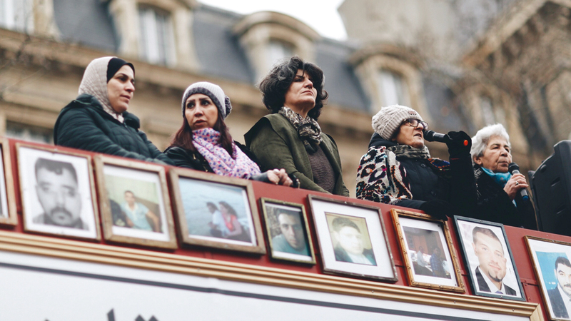 ناشطون بجانب صور نشطاء معتقلين في سجون النظام السوري. أرشيفية