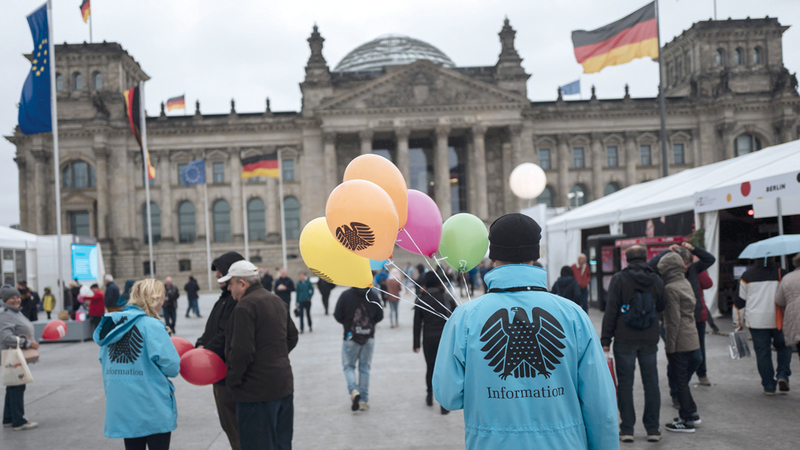 رجل يوزع بالونات رسم عليها شعار النسر الألماني مجاناً في ذكرى يوم وحدة ألمانيا.  إي.بي.إيه