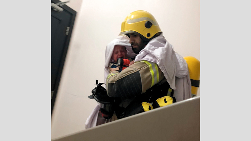 رجل إطفاء ينقذ طفلاً من الدخان. من المصدر