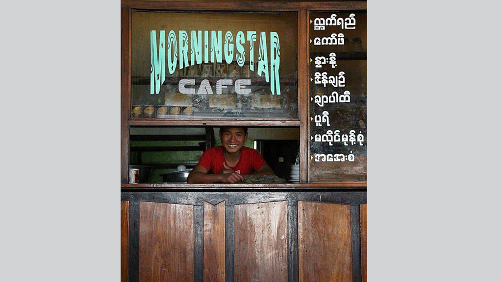 شاب يبتسم للكاميرا مع بداية يوم عمل جديد في محل لبيع القهوة والشاي، ميانمار