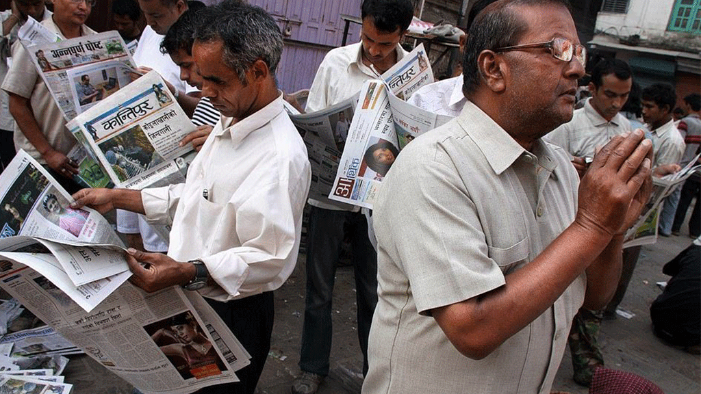 قراءة صباحية لأهم العناوين الإخبارية، فيما يغلق أحد الرجال عينيه لينغمس في الصلاة والدعاء