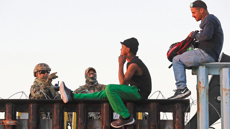 مهاجرون يجلسون على بعض المنشآت في الحدود الفاصلة بين الولايات المتحدة والمكسيك.  أ.ب