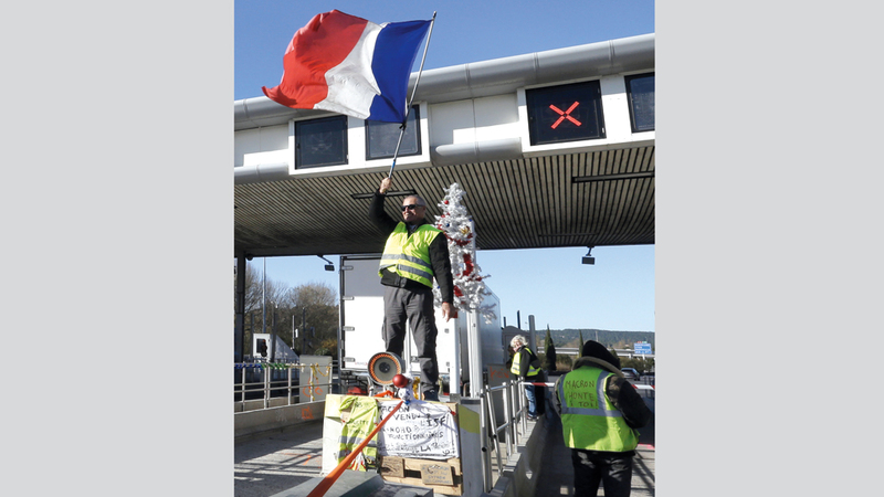 أحد محتجي «السترات الصفراء» يرفع العلم الفرنسي. أ.ب