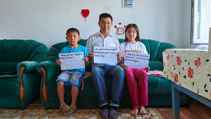 «إسلام» وابنته وابنه يرفعون لافتات تطالب بإطلاق سراح أمهم خلال اعتقالها في كازاخستان.  غيتي