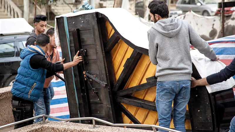 طلاب في المعهد يحملون البيانو الضخم الذي أعادت النرويج تأهيله بعد إعطابه بسبب ظروف الحرب والحصار. من المصدر