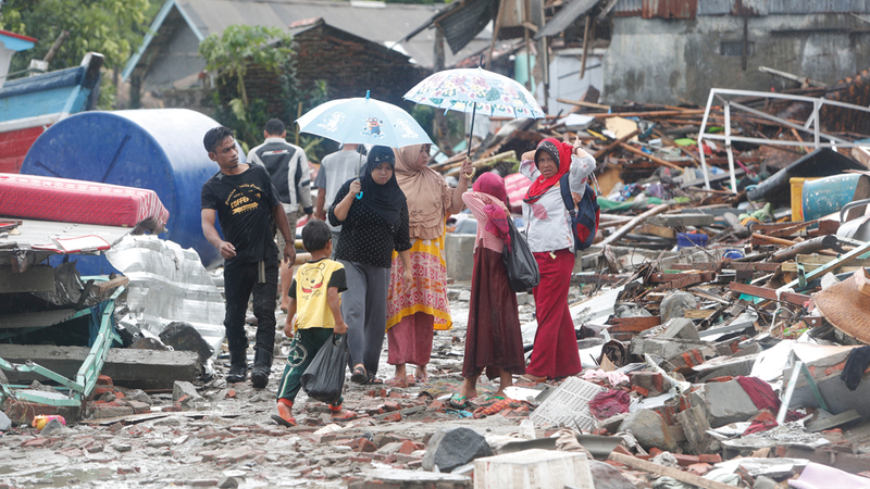 سكان محليون في إندونيسيا يسيرون بين الأنقاض. إي.بي.إيه