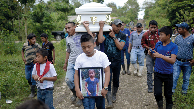 طفل يحمل صورة للطفلة المتوفاة وهو يتقدم موكب جنازتها.  أ.ف.ب