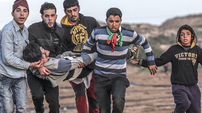 فلسطينيون يحملون مصاباً في المواجهات مع الاحتلال شمال غزة.

إي.بي.إيه