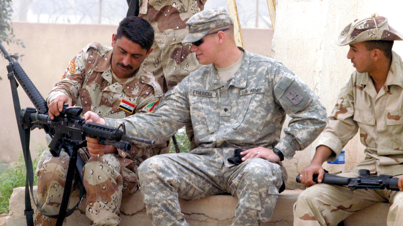 جندي أميركي يدرّب أحد الجنود العراقيين على كيفية استخدام السلاح. إي.بي.إيه