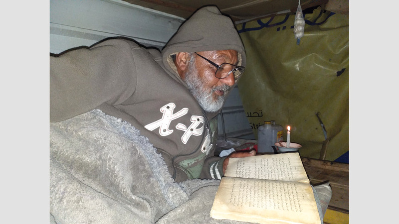 صالح الجوجو يطالع كتاباً جمعه بنفسه في خيمته المتواضعة. الإمارات اليوم