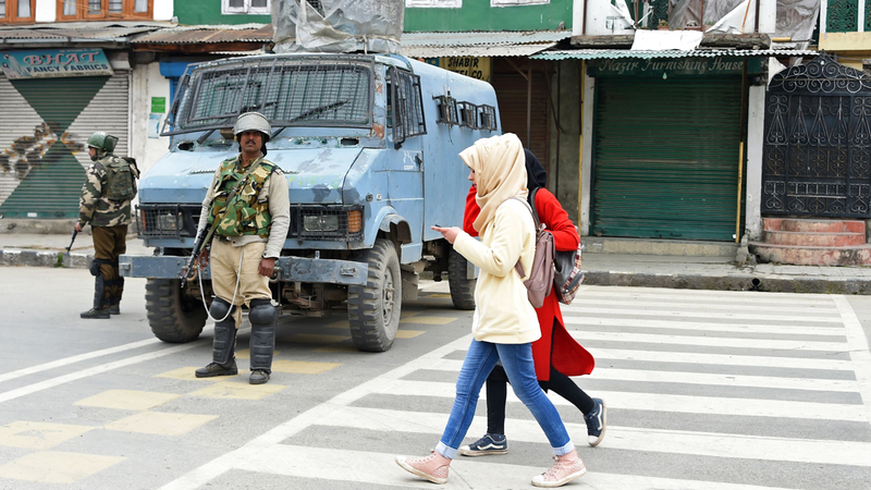 فتاتان كشميريتان تسيران من أمام قوات هندية في سريناجار. أ.ف.ب