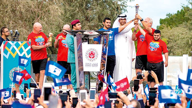 السبوسي (يمين) يرفع «شعلة الأمل». من المصدر