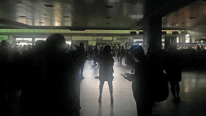 المسافرون يقفون وسط الظلام في صالة المغادرين بمطار سيمون بوليفار بالعاصمة كراكاس.  رويترز