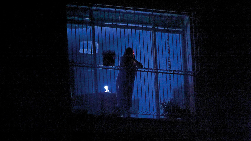 مواطن فنزويلي يلقي نظرة على الشوارع المظلمة  عبر نافذة بيته في كراكاس.  أ.ف.ب